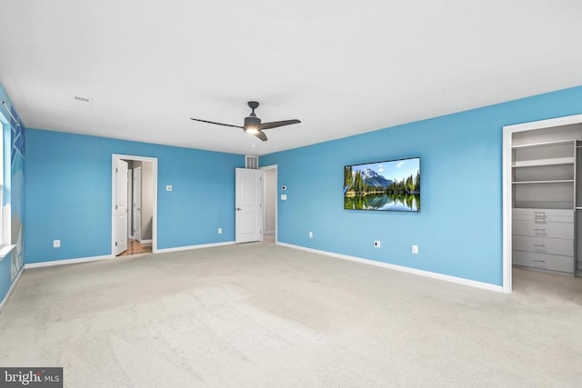 unfurnished bedroom featuring baseboards, visible vents, carpet, and a walk in closet