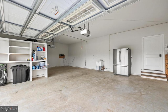 garage featuring freestanding refrigerator, a garage door opener, and a sink