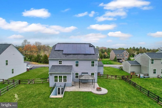 rear view of house featuring a fire pit, solar panels, a patio area, a gazebo, and roof with shingles