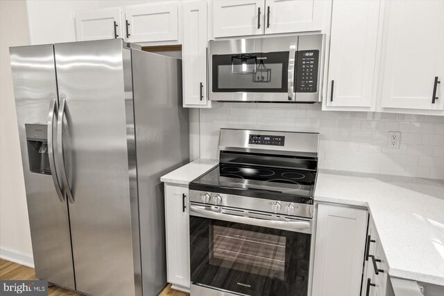 kitchen with white cabinetry, tasteful backsplash, light stone countertops, and appliances with stainless steel finishes