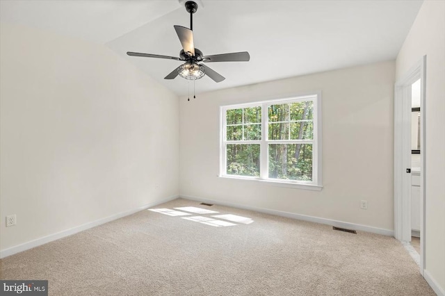 empty room with vaulted ceiling, light colored carpet, and ceiling fan