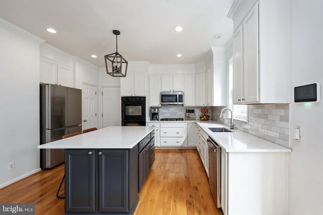 5915 Copper Mountain Dr W, Spotsylvania, VA 22553 - kitchen with appliances with stainless steel finishes, white cabinetry, a kitchen island, light countertops, and backsplash