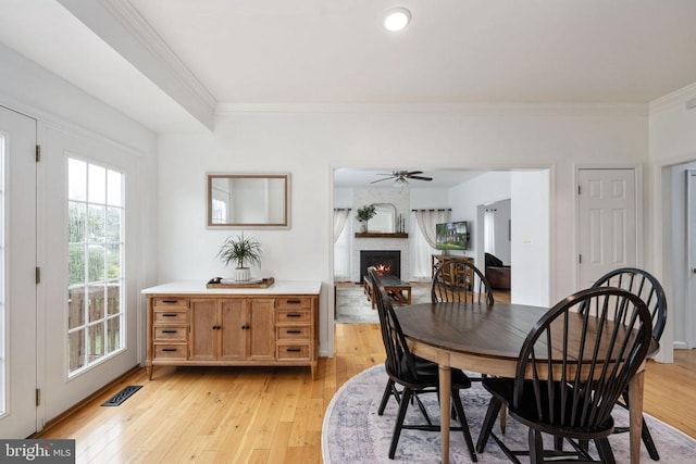 5915 Copper Mountain Dr W, Spotsylvania, VA 22553 - dining room featuring a warm lit fireplace, ornamental molding, light wood-style flooring, and ceiling fan