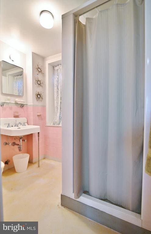 301 Mountain Top Dr, Luray, VA 22835 - bathroom featuring a sink, curtained shower, a wainscoted wall, tile walls, and concrete flooring