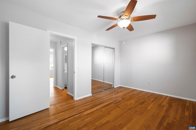 unfurnished bedroom featuring ceiling fan, a closet, baseboards, and wood finished floors