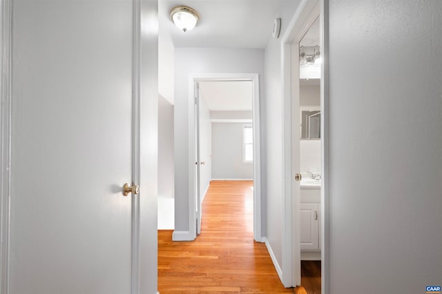 hall featuring baseboards and light wood-type flooring