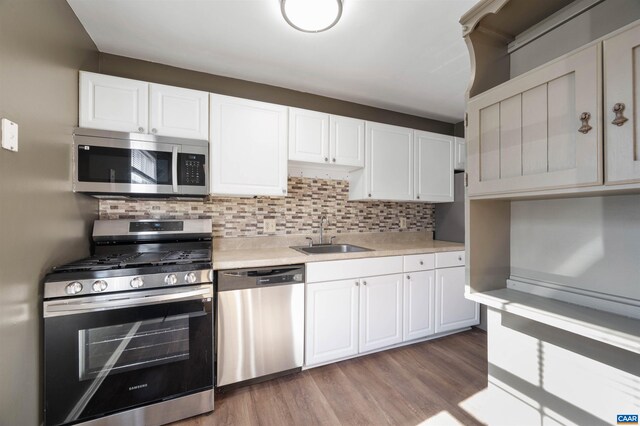 kitchen featuring stainless steel appliances, a sink, backsplash, light countertops, and white cabinets
