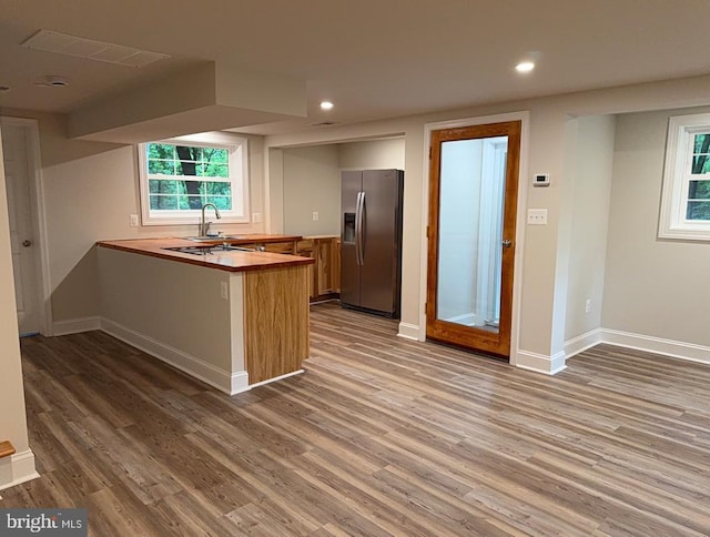  - kitchen featuring stainless steel refrigerator with ice dispenser, a peninsula, wood finished floors, recessed lighting, and butcher block countertops
