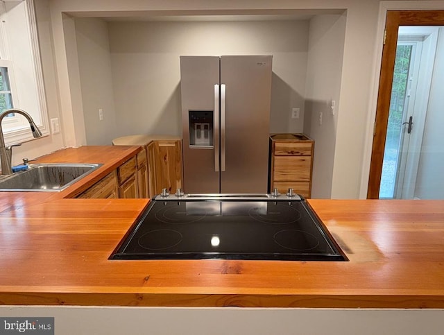  - kitchen featuring stainless steel fridge with ice dispenser, cooktop, plenty of natural light, and wooden counters