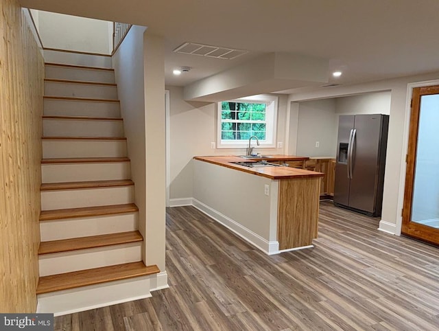  - kitchen with stainless steel fridge, wooden counters, wood finished floors, a peninsula, and recessed lighting