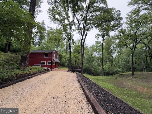  - view of yard featuring dirt driveway and a view of trees