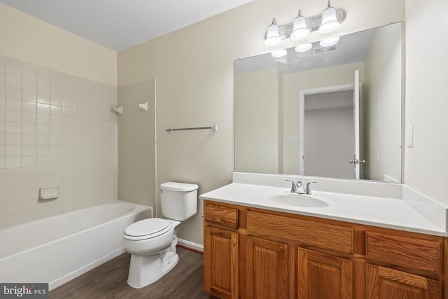 bathroom with wood finished floors, toilet, vanity, and bathtub / shower combination