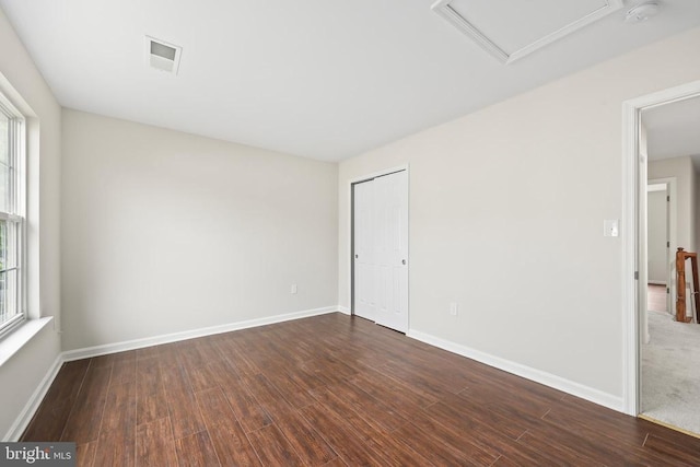 spare room with dark wood-style flooring, a smoke detector, attic access, and baseboards