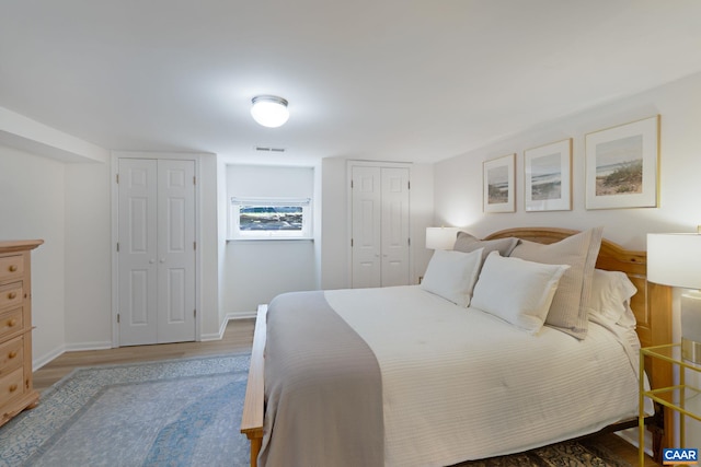 bedroom featuring multiple closets, wood finished floors, and baseboards