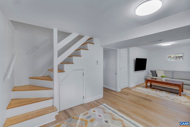 below grade area featuring wood finished floors, stairway, and baseboards