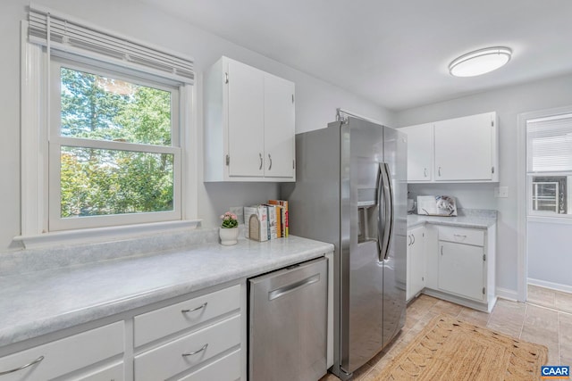 kitchen with stainless steel appliances, light countertops, white cabinetry, and baseboards