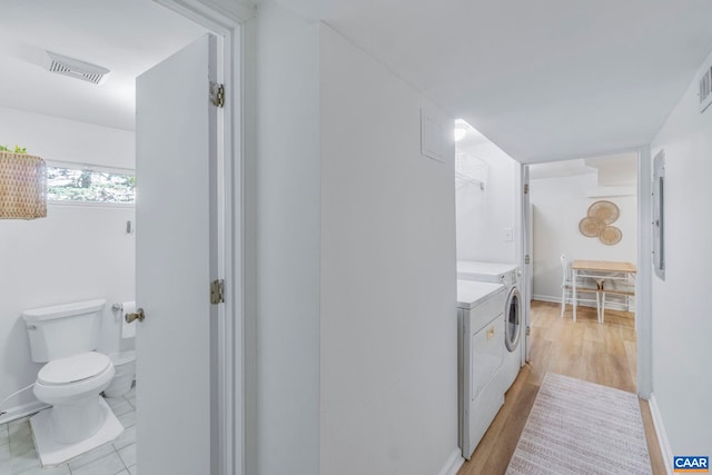 bathroom featuring washer and clothes dryer, toilet, baseboards, and wood finished floors