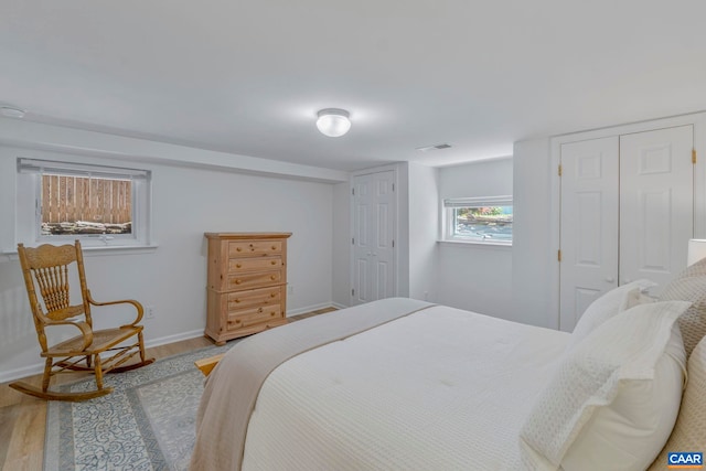 bedroom featuring wood finished floors, baseboards, and multiple closets