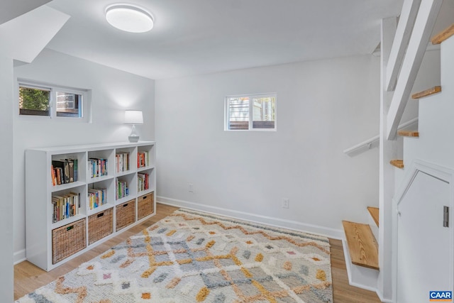 sitting room with healthy amount of natural light, wood finished floors, and stairs