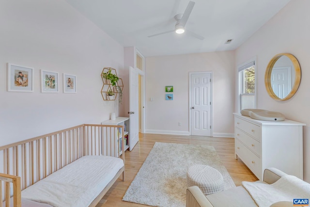 bedroom featuring light wood-style flooring, a ceiling fan, and baseboards