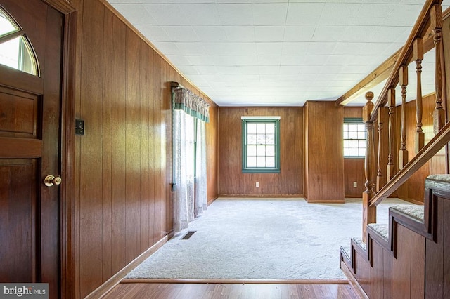  - foyer entrance featuring wood walls, stairs, and wood finished floors