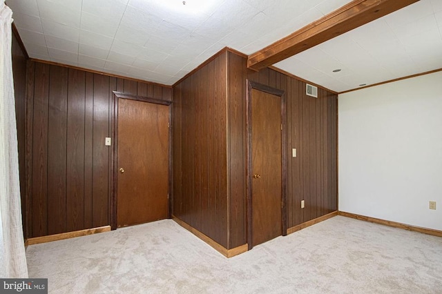  - basement with carpet, wood walls, and ornamental molding