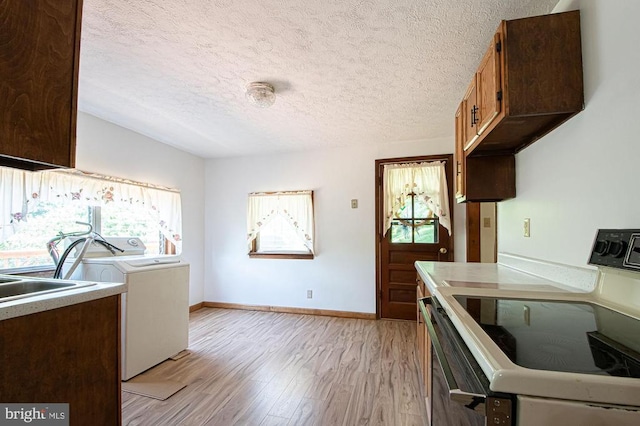  - kitchen featuring electric range, independent washer and dryer, light wood-style floors, a textured ceiling, and light countertops