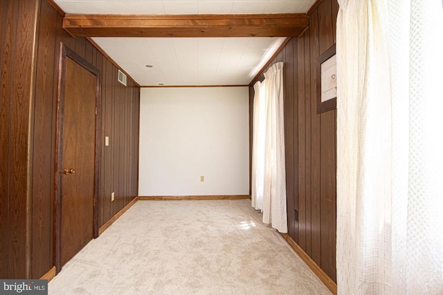  - unfurnished bedroom featuring wooden walls, light carpet, beamed ceiling, and ornamental molding