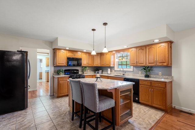 5409 Smith Creek Rd, New Market, VA 22844 - kitchen with black appliances, light stone countertops, an island with sink, decorative light fixtures, and brown cabinets