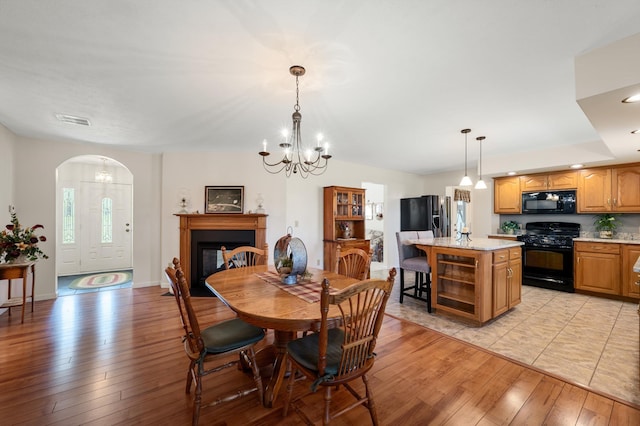 5409 Smith Creek Rd, New Market, VA 22844 - dining room with light wood-style flooring, a glass covered fireplace, a chandelier, arched walkways, and wine cooler