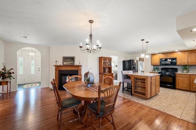 5409 Smith Creek Rd, New Market, VA 22844 - dining area featuring light wood-style floors, a glass covered fireplace, a chandelier, wine cooler, and arched walkways