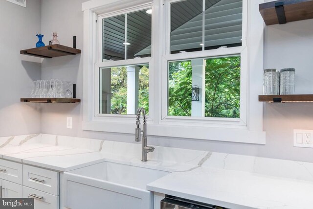 kitchen with open shelves, a sink, white cabinets, and light stone countertops