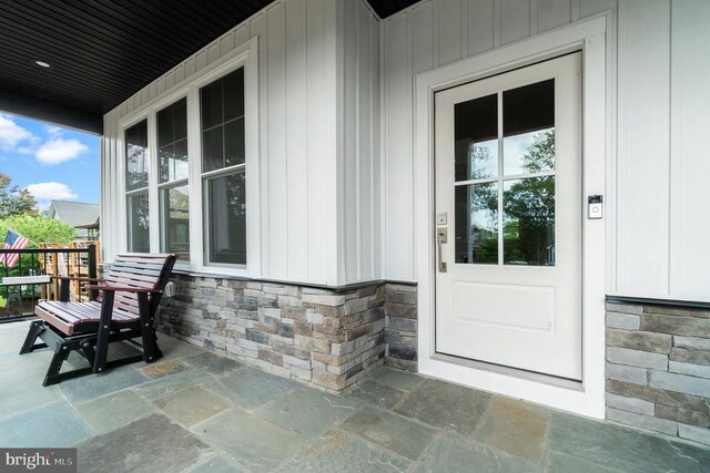 property entrance with a porch, stone siding, and board and batten siding