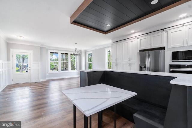 kitchen with stainless steel appliances, crown molding, plenty of natural light, white cabinets, and a chandelier