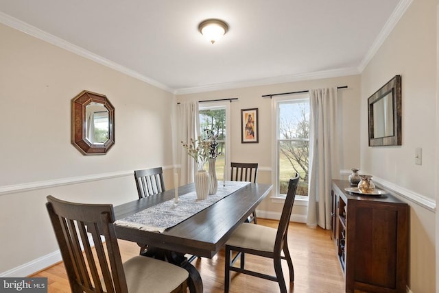 dining room with crown molding, light wood-style flooring, and baseboards