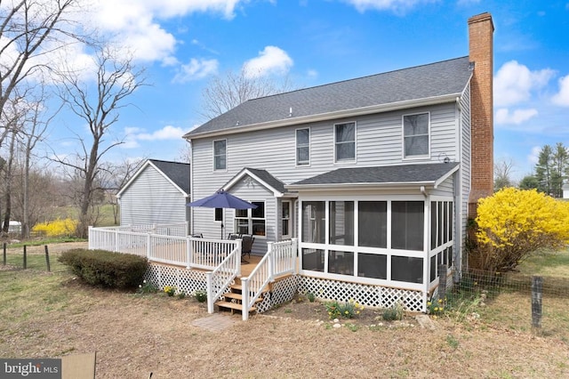 rear view of property with a sunroom, a chimney, a deck, and fence