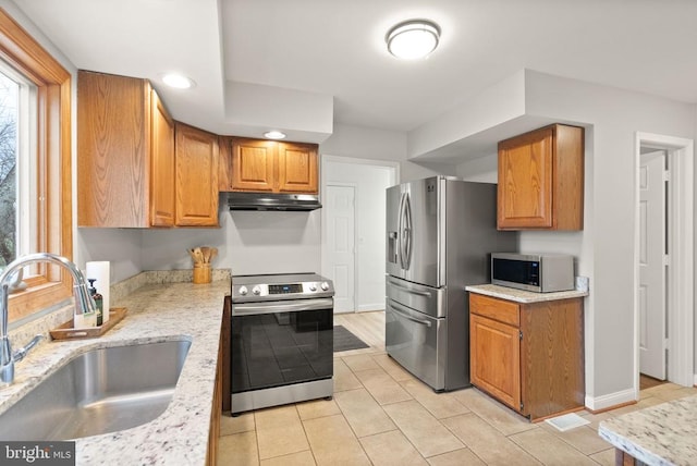 kitchen with stainless steel appliances, a sink, under cabinet range hood, brown cabinets, and recessed lighting