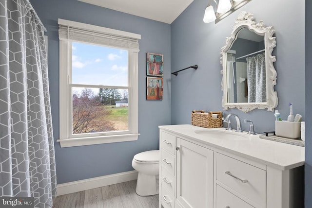 bathroom featuring healthy amount of natural light, baseboards, toilet, and vanity