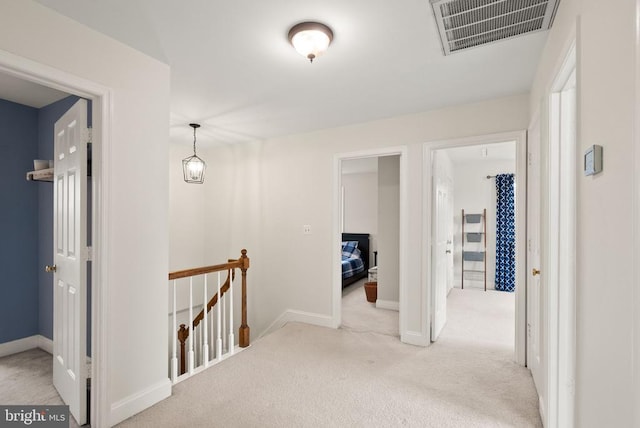 hallway with an upstairs landing, carpet, and baseboards