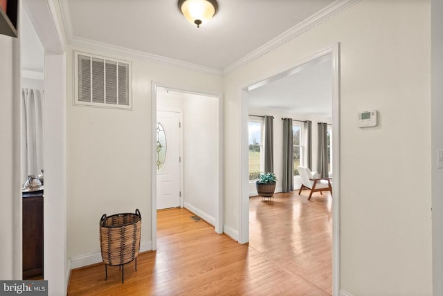 foyer featuring light wood-type flooring, crown molding, and baseboards