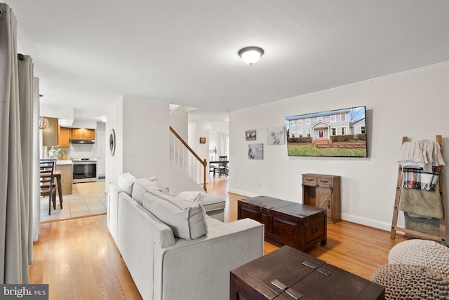 living area with stairs, light wood-style floors, ornamental molding, and baseboards