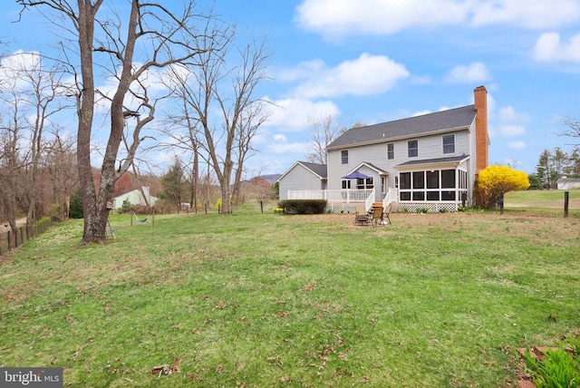 view of green lawn featuring a sunroom and a deck