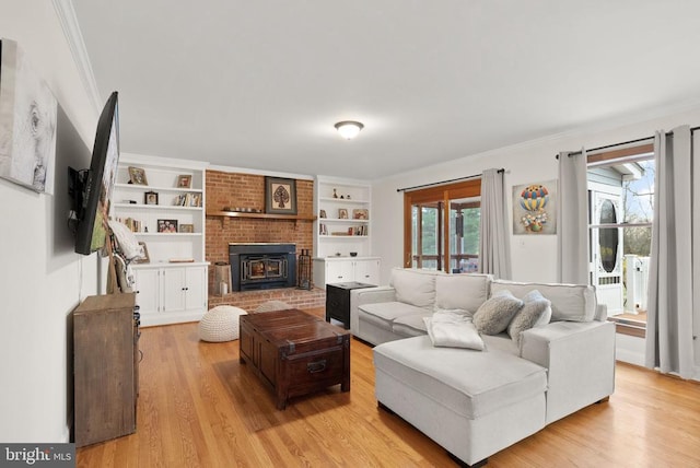 living area with ornamental molding, light wood-style floors, a brick fireplace, and built in features