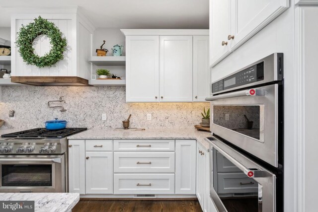 10605 Springvale Ln, Spotsylvania, VA 22551 - kitchen featuring appliances with stainless steel finishes, open shelves, decorative backsplash, white cabinets, and light stone countertops