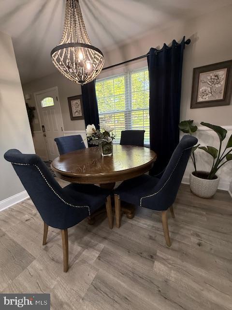 dining area with baseboards, healthy amount of natural light, light wood-style flooring, and a chandelier