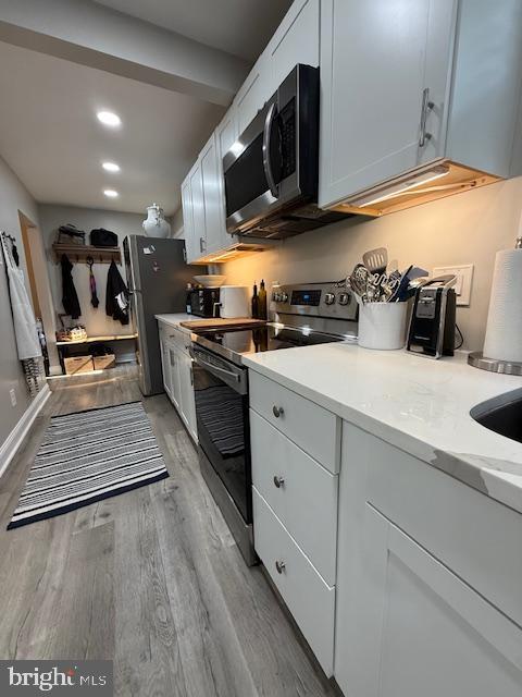 kitchen featuring stainless steel appliances, light wood finished floors, light countertops, and recessed lighting