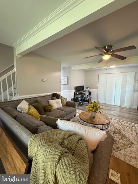 living room with wood finished floors, a ceiling fan, wainscoting, and an office area