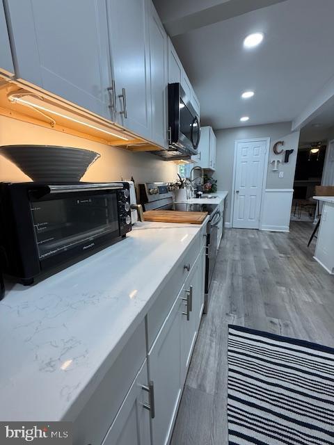 kitchen with appliances with stainless steel finishes, light countertops, light wood-style floors, recessed lighting, and white cabinetry