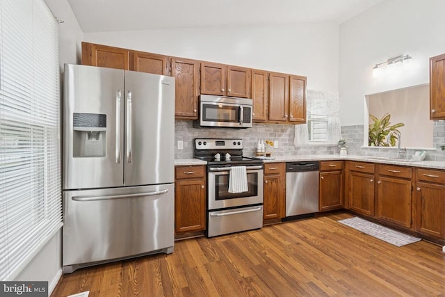 10804 Cobblestone Dr, Spotsylvania, VA 22553 - kitchen with stainless steel appliances, lofted ceiling, backsplash, dark wood-style flooring, and brown cabinets