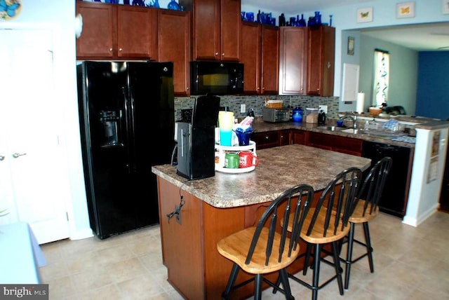  - kitchen featuring black appliances, tasteful backsplash, a kitchen island, a peninsula, and a breakfast bar area